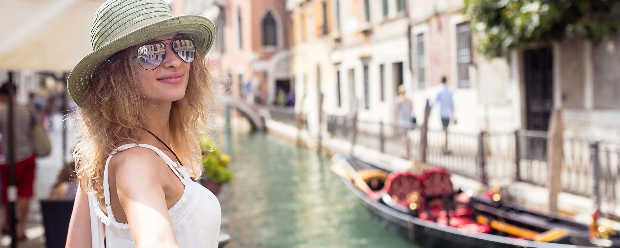 Chica mirando a cámara al lado de una góndola en Venecia.